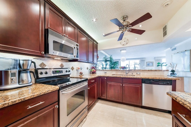 kitchen featuring ceiling fan, light stone counters, light tile patterned floors, sink, and appliances with stainless steel finishes