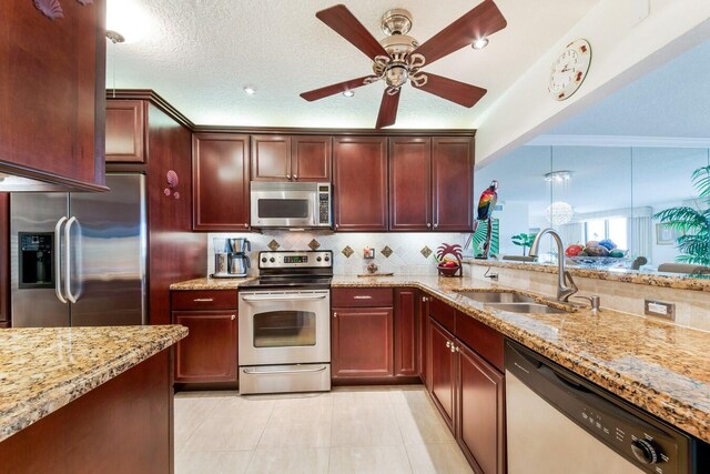 kitchen featuring ceiling fan, sink, decorative light fixtures, stainless steel appliances, and light stone countertops