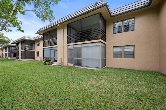 rear view of property with a yard and a balcony