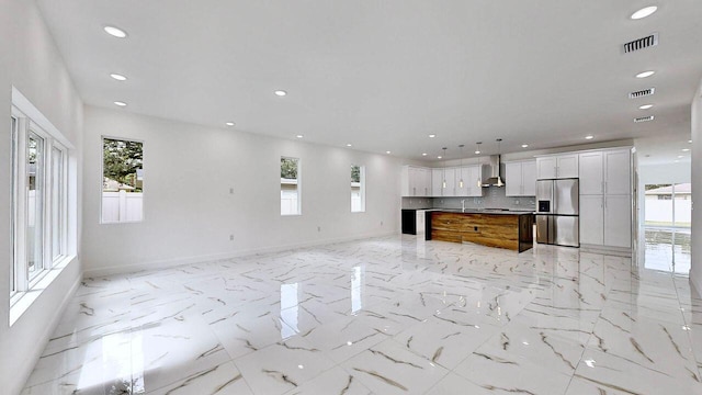 unfurnished living room featuring sink, a healthy amount of sunlight, and light tile patterned floors