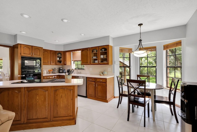 kitchen featuring light tile patterned floors, hanging light fixtures, backsplash, black appliances, and a textured ceiling