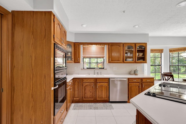 kitchen with sink, black appliances, a textured ceiling, light tile patterned flooring, and decorative backsplash