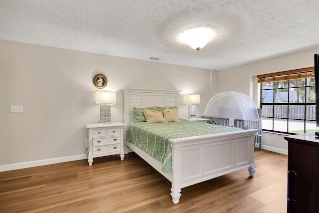 bedroom with hardwood / wood-style floors and a textured ceiling