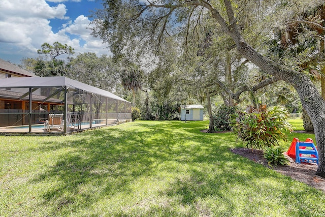 view of yard featuring a storage unit, a fenced in pool, and glass enclosure