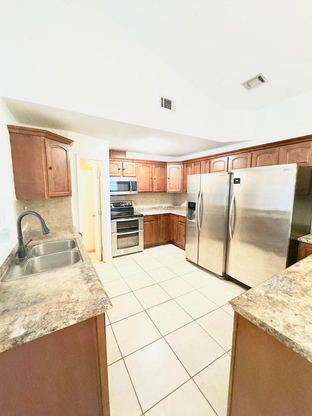 kitchen featuring light tile patterned flooring, appliances with stainless steel finishes, backsplash, and sink