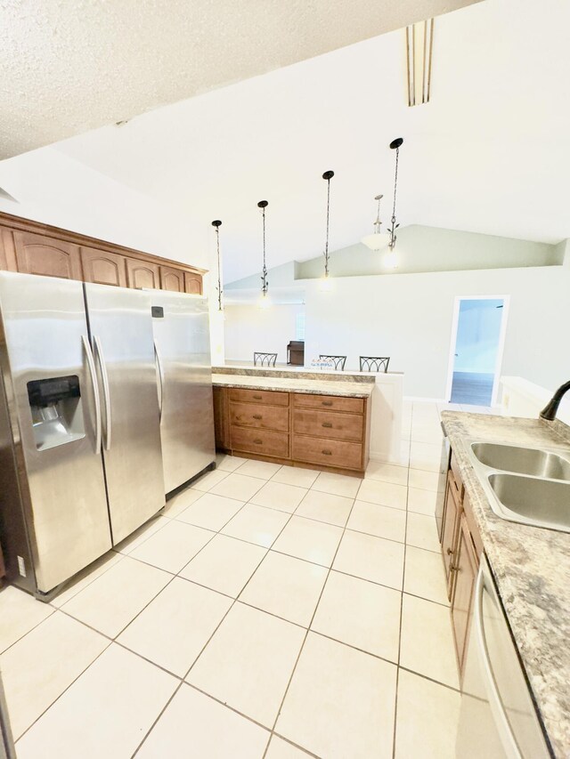 kitchen featuring hanging light fixtures, light tile patterned floors, stainless steel fridge with ice dispenser, and sink