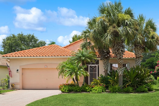 mediterranean / spanish home featuring a garage and a front yard