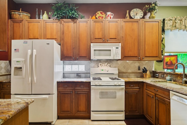 kitchen featuring tasteful backsplash, sink, white appliances, and light stone countertops