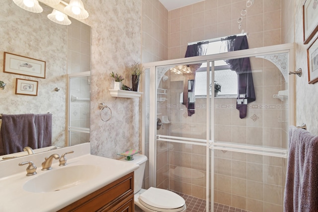 bathroom with a shower with door, vanity, and toilet