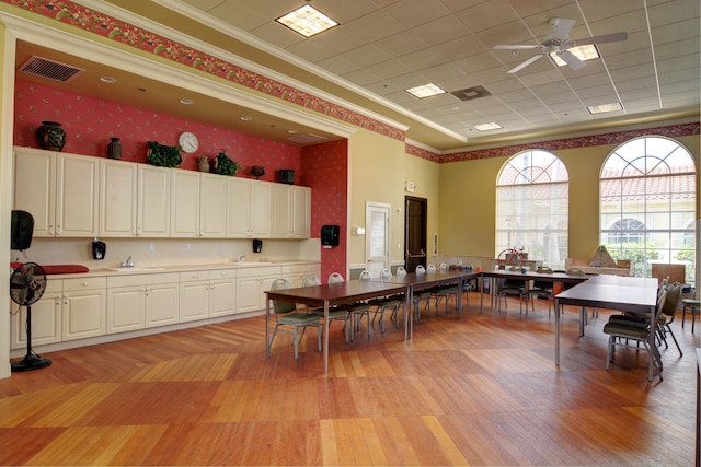 dining area featuring crown molding, sink, ceiling fan, and light hardwood / wood-style floors