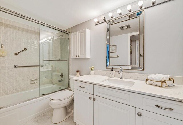 full bathroom with tile patterned floors, vanity, bath / shower combo with glass door, and toilet