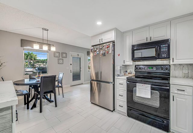 kitchen featuring pendant lighting, black appliances, white cabinets, and backsplash