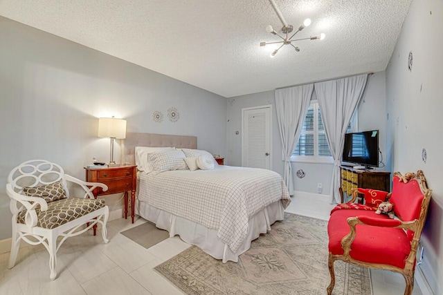 tiled bedroom featuring an inviting chandelier and a textured ceiling