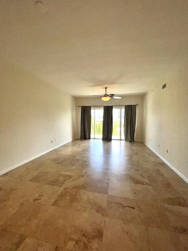 unfurnished room with ceiling fan, visible vents, and baseboards