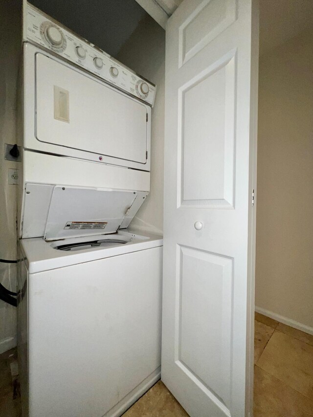 clothes washing area featuring light tile patterned flooring and stacked washing maching and dryer