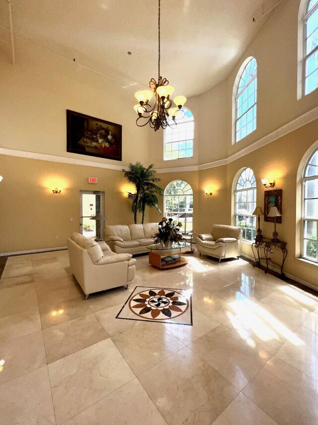 living room featuring a healthy amount of sunlight, light tile patterned floors, an inviting chandelier, and a high ceiling