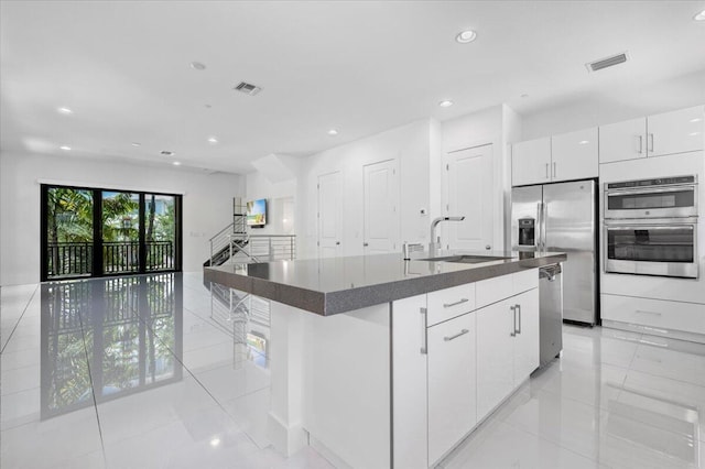 kitchen with white cabinets, a center island with sink, stainless steel appliances, and sink