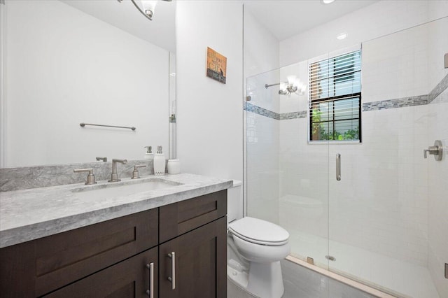 bathroom with vanity, toilet, and a shower with door