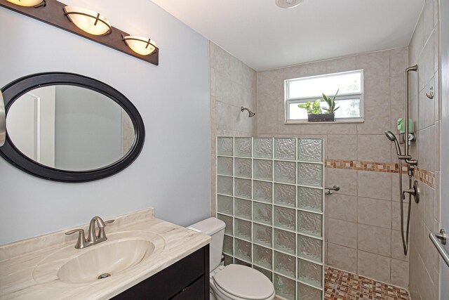 bathroom with toilet, vanity, and a tile shower