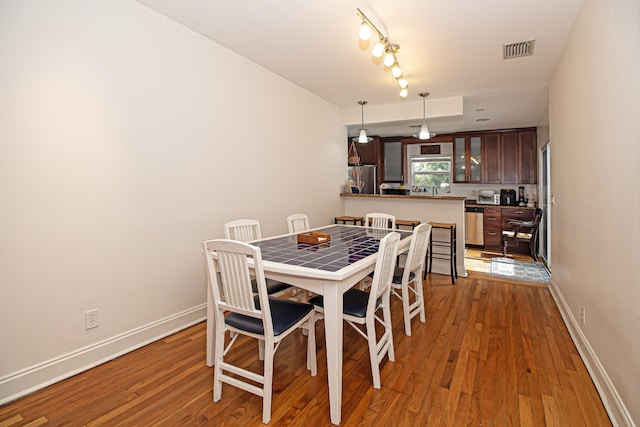 dining space featuring rail lighting and hardwood / wood-style floors