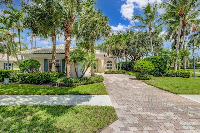 mediterranean / spanish-style house with a tiled roof, a front lawn, decorative driveway, and stucco siding