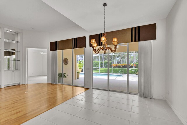 spare room featuring ceiling fan with notable chandelier and wood finished floors