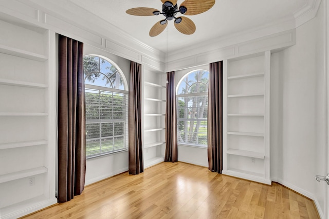 empty room featuring baseboards, built in features, and light wood-style floors