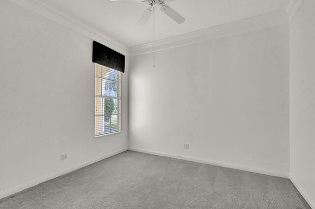 carpeted spare room featuring ceiling fan, ornamental molding, and baseboards