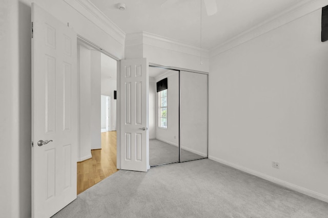 unfurnished bedroom featuring carpet floors, baseboards, ornamental molding, and a closet