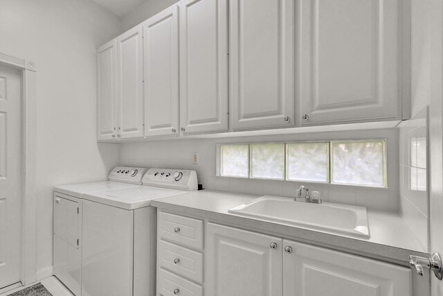 laundry area with cabinet space, washer and dryer, a wealth of natural light, and a sink