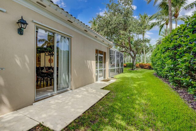 view of yard with glass enclosure and a patio area