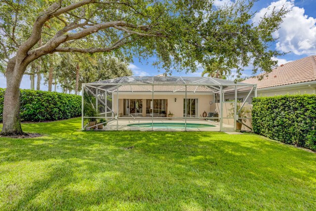 back of property featuring a patio, stucco siding, a lawn, glass enclosure, and an outdoor pool