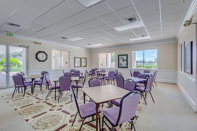 carpeted dining space featuring a drop ceiling and ornamental molding