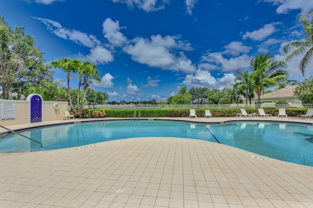 community pool with fence and a patio