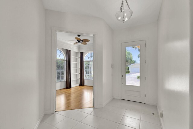 foyer featuring a ceiling fan, a healthy amount of sunlight, baseboards, and light tile patterned floors