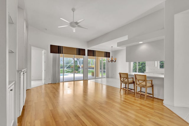 living room featuring light wood-type flooring and ceiling fan with notable chandelier