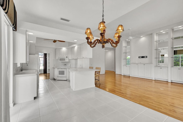 kitchen with white cabinets, white appliances, a breakfast bar area, and light countertops