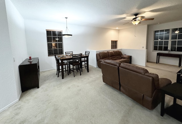 living room with a textured ceiling, light colored carpet, and ceiling fan