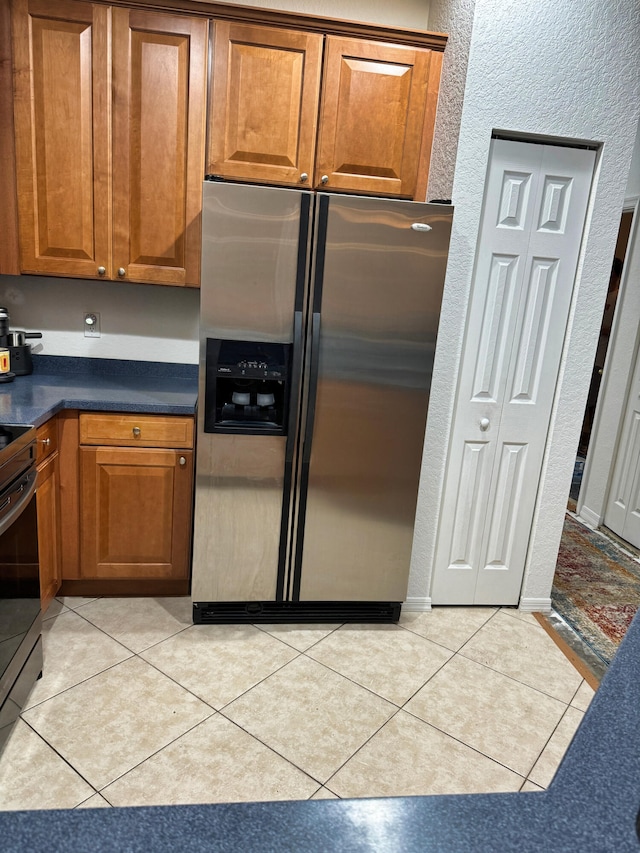 kitchen with stainless steel fridge, black stove, and light tile patterned floors