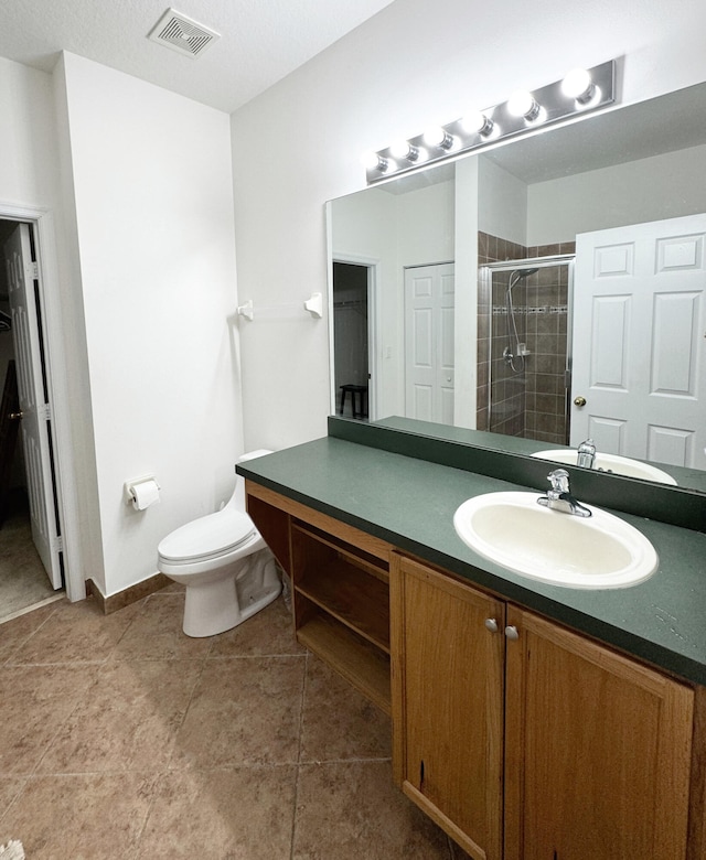 bathroom with tile patterned floors, a shower with shower door, toilet, and vanity