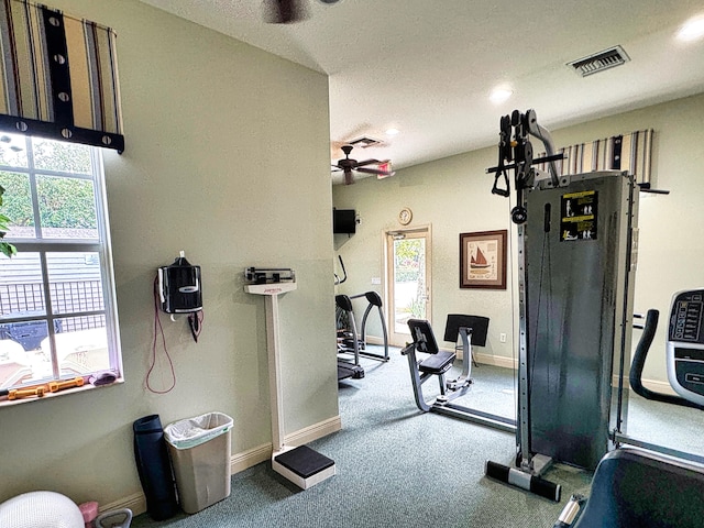 exercise room with ceiling fan and a textured ceiling