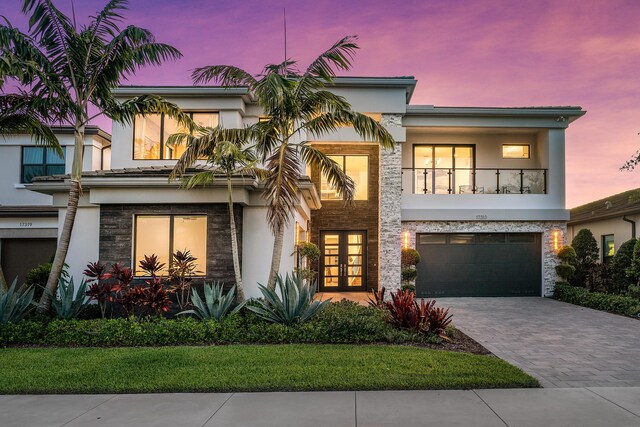 view of front of property featuring a balcony, a garage, and french doors