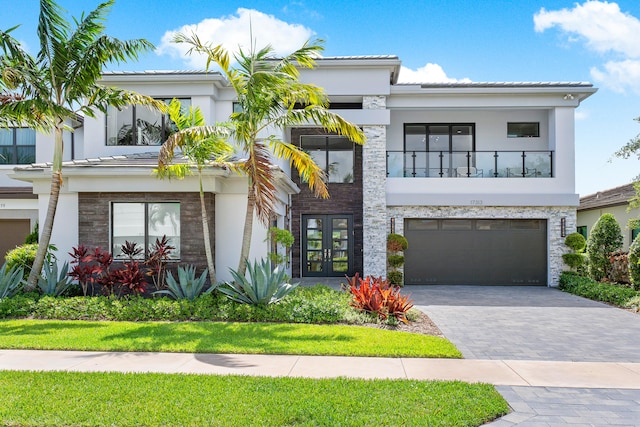 view of front facade featuring a garage, a balcony, and french doors