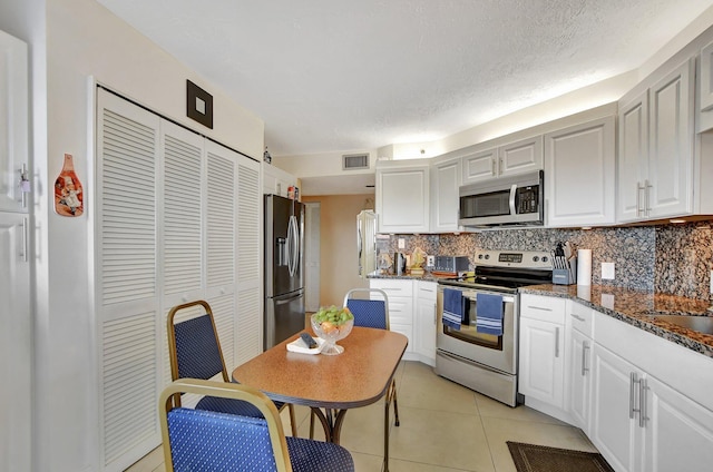 kitchen featuring tasteful backsplash, white cabinetry, appliances with stainless steel finishes, and dark stone counters