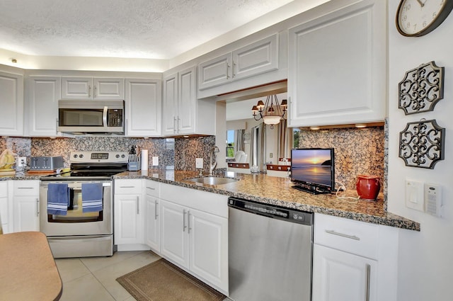 kitchen featuring dark stone countertops, sink, stainless steel appliances, and white cabinets