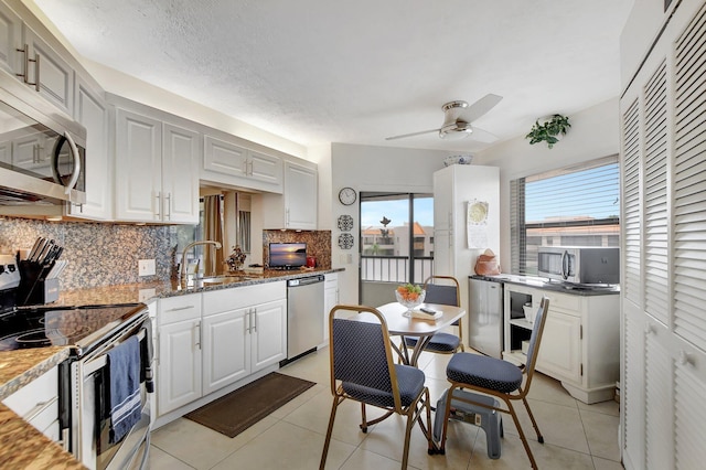 kitchen with sink, white cabinetry, stainless steel appliances, light stone countertops, and decorative backsplash