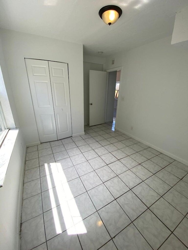 unfurnished bedroom featuring light tile patterned flooring and a closet