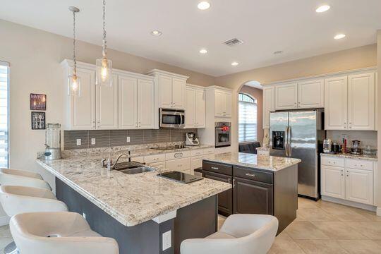 kitchen with sink, white cabinetry, kitchen peninsula, hanging light fixtures, and appliances with stainless steel finishes