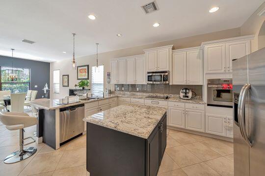 kitchen featuring a kitchen island, appliances with stainless steel finishes, and decorative light fixtures