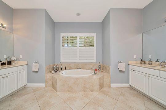 bathroom with tile patterned floors, tiled bath, and vanity